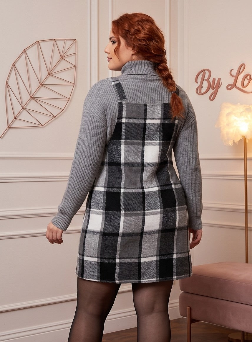 Peto vestido pichi corto para mujer curvy en estampado clásico de cuadros escoceses con corte línea A, tirantes anchos con botones y bolsillo frontal plastrón, confeccionado en mezcla de poliéster cálido, disponible en tonos verde botella, marrón camel y gris con negro sobre jersey de punto.