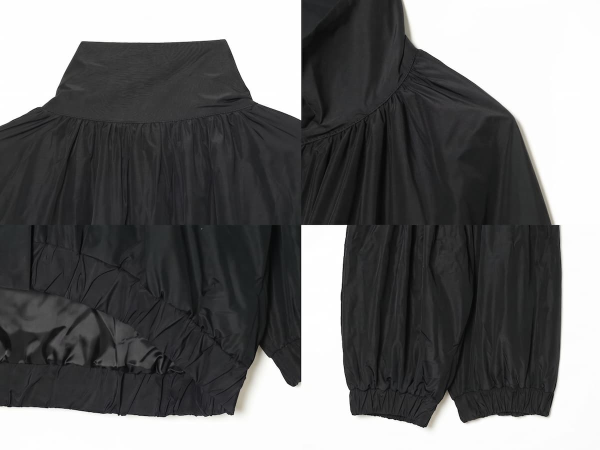 Detalle del dobladillo, costuras y acabado de Chaqueta estilo bomber negra de corte oversized con cuello alto alzado, cierre de cremallera frontal y mangas largas abullonadas con puños elásticos, fabricada en tejido ligero de poliéster para un look urbano y casual.