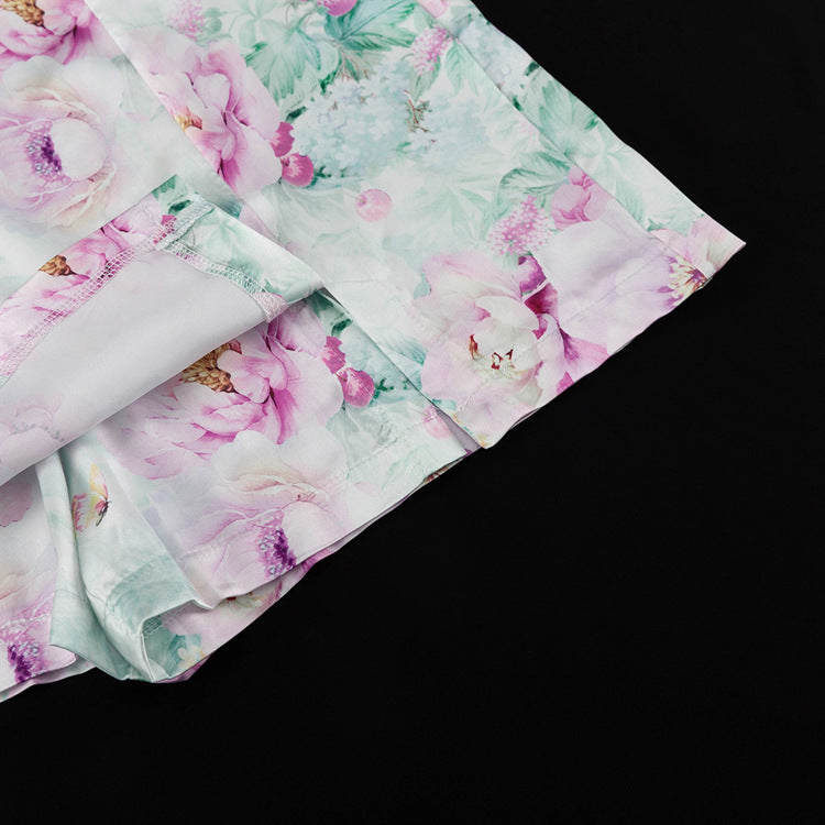 Detalle del dobladillo, costuras y acabado de conjunto de dos piezas floral en tonos rosa y pastel: blazer corto cropped de manga larga con solapas y botones frontales combinado con falda-pantalón mini de tiro alto a juego
