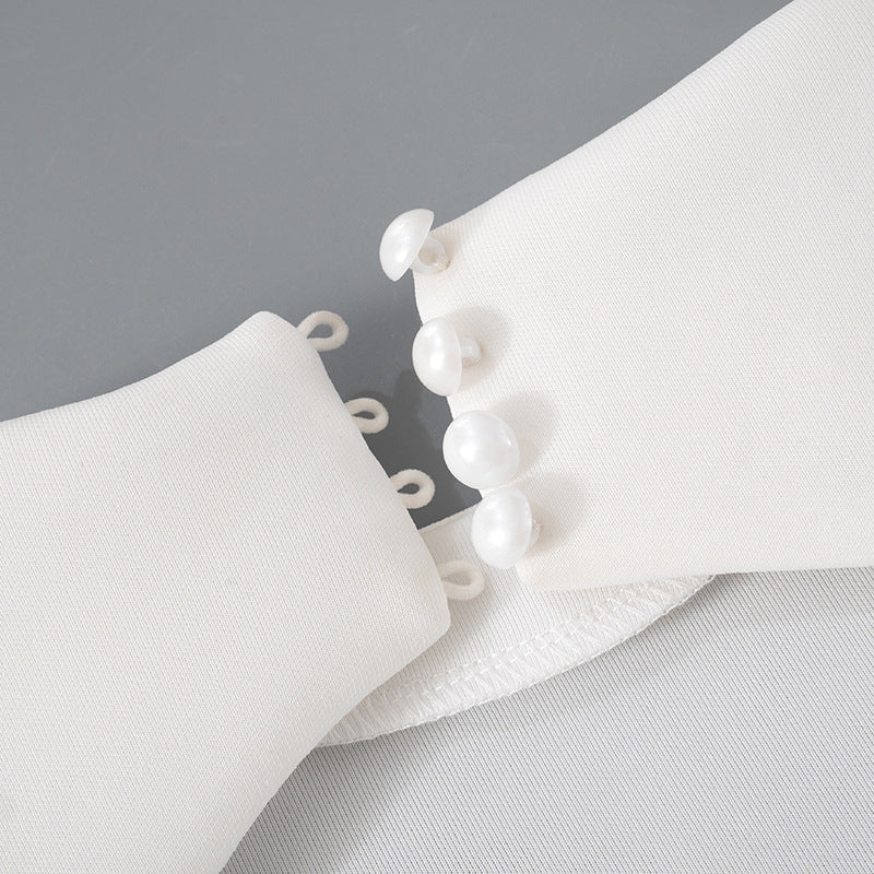 Detalle del dobladillo, costuras y acabado de Vestido corto entallado de manga larga en color liso con cuello subido y falda de línea A, detalle de abertura en la espalda con botones de perla y cierre de cremallera.