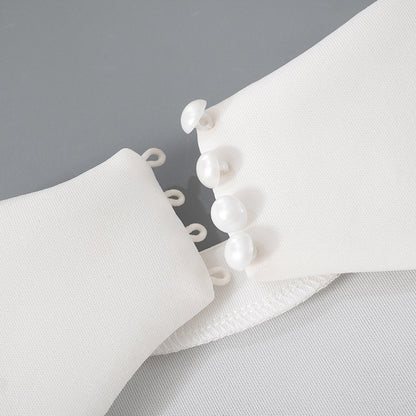 Detalle del dobladillo, costuras y acabado de Vestido corto entallado de manga larga en color liso con cuello subido y falda de línea A, detalle de abertura en la espalda con botones de perla y cierre de cremallera.