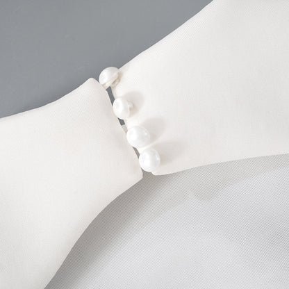 Detalle del dobladillo, costuras y acabado de Vestido corto entallado de manga larga en color liso con cuello subido y falda de línea A, detalle de abertura en la espalda con botones de perla y cierre de cremallera.