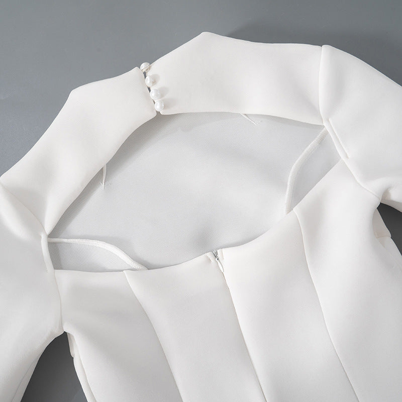 Detalle del dobladillo, costuras y acabado de Vestido corto entallado de manga larga en color liso con cuello subido y falda de línea A, detalle de abertura en la espalda con botones de perla y cierre de cremallera.