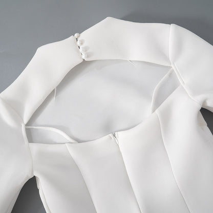 Detalle del dobladillo, costuras y acabado de Vestido corto entallado de manga larga en color liso con cuello subido y falda de línea A, detalle de abertura en la espalda con botones de perla y cierre de cremallera.
