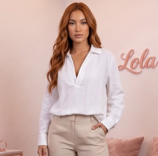 Blusa fluida de mujer en color blanco con cuello camisero abierto en V, diseño frontal cruzado drapeado, manga larga holgada con puño de botón y corte suelto con bajo asimétrico