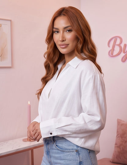 Blusa fluida de mujer en color blanco con cuello camisero abierto en V, diseño frontal cruzado drapeado, manga larga holgada con puño de botón y corte suelto con bajo asimétrico