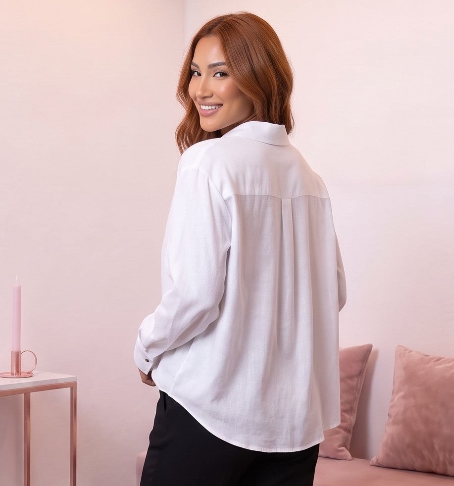 Blusa fluida de mujer en color blanco con cuello camisero abierto en V, diseño frontal cruzado drapeado, manga larga holgada con puño de botón y corte suelto con bajo asimétrico