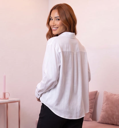 Blusa fluida de mujer en color blanco con cuello camisero abierto en V, diseño frontal cruzado drapeado, manga larga holgada con puño de botón y corte suelto con bajo asimétrico