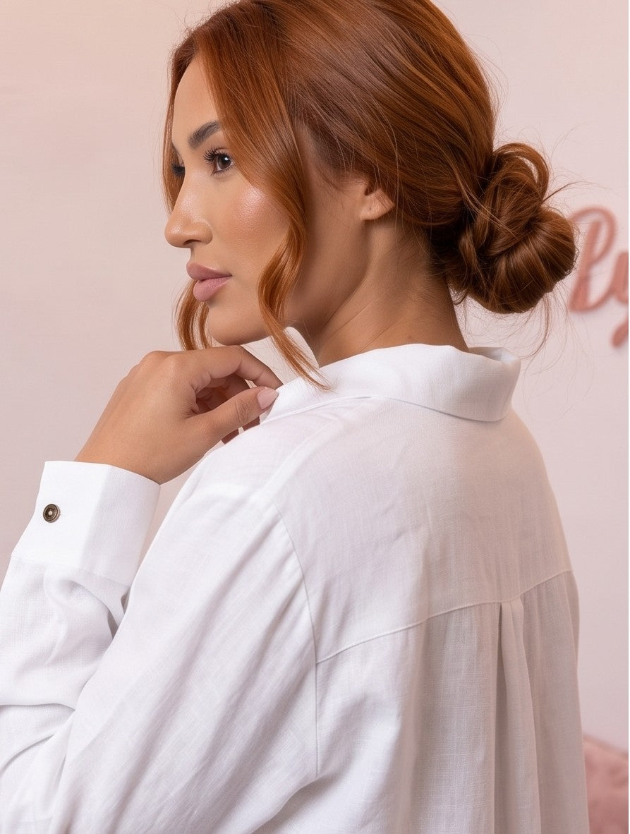 Blusa fluida de mujer en color blanco con cuello camisero abierto en V, diseño frontal cruzado drapeado, manga larga holgada con puño de botón y corte suelto con bajo asimétrico