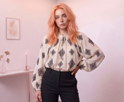 Blusa femenina de estilo boho en tono crema con estampado étnico geométrico negro, cuello mao fruncido con lazo y mangas largas abullonadas con puño elástico