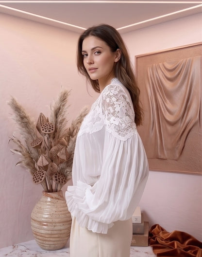 blusa de estilo bohemio romántico en dos colores: blanco y negro. La blusa destaca por su escote en V profundo con encaje floral detallado y sus mangas largas abullonadas con puños con volantes plisados.