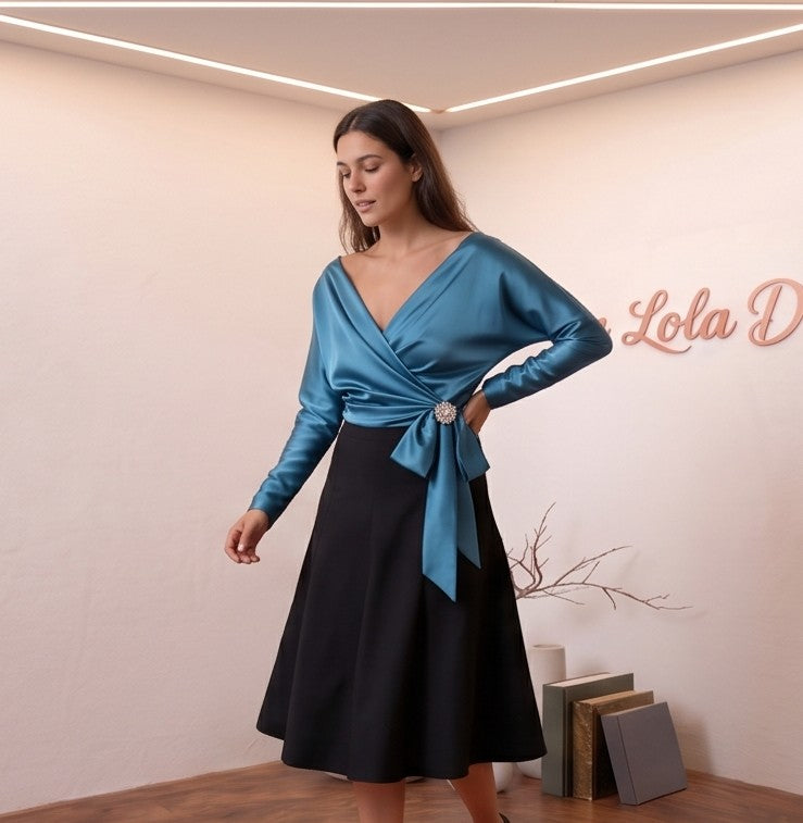 Blusa de satén de seda con diseño cruzado, escote en V y lazada lateral con detalle de broche. Disponible en varios colores: amarillo vibrante, azul cielo, blanco roto y champán. Manga larga y corte elegante y sofisticado.