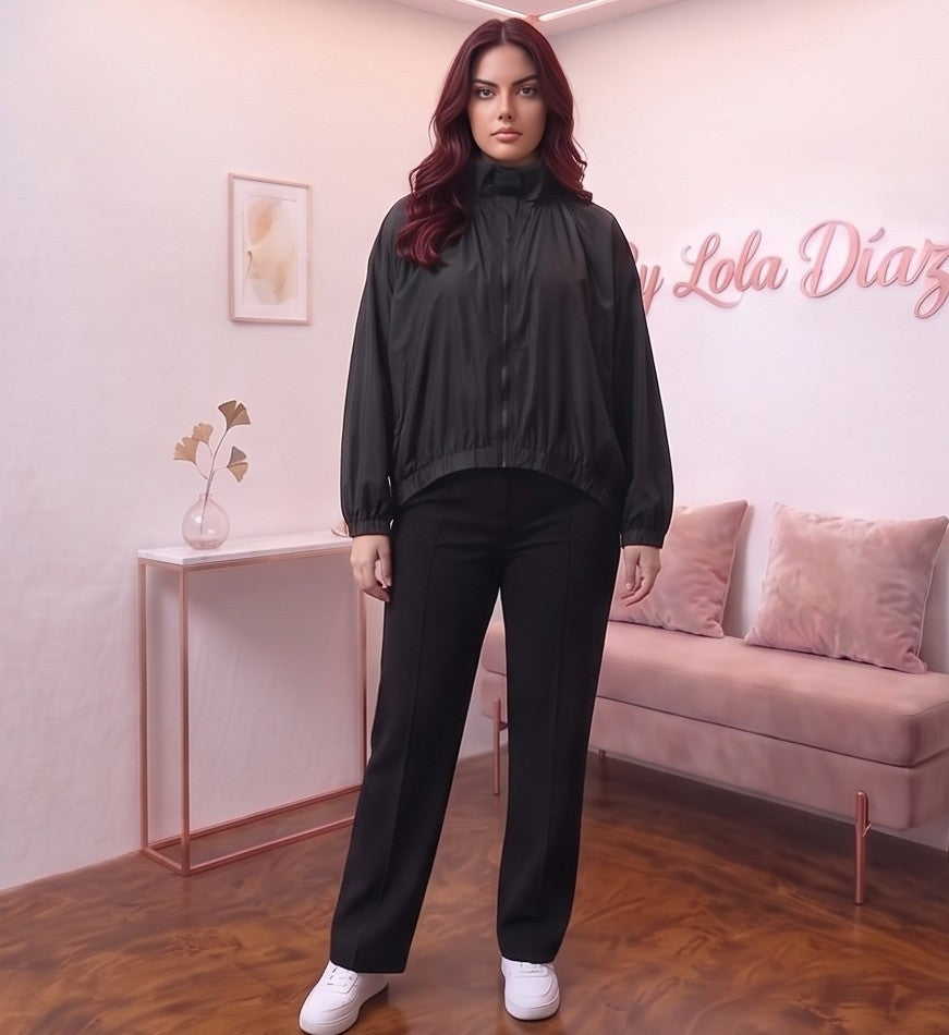 Chaqueta estilo bomber negra de corte oversized con cuello alto alzado, cierre de cremallera frontal y mangas largas abullonadas con puños elásticos, fabricada en tejido ligero de poliéster para un look urbano y casual.