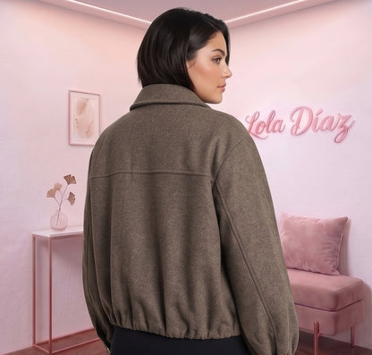 Cazadora estilo bomber de corte holgado para mujer en paño tipo lana suave, disponible en marrón caqui oscuro y negro, con cuello camisero de solapa, cierre frontal de cremallera metálica, puños ajustados y bajo elástico fruncido