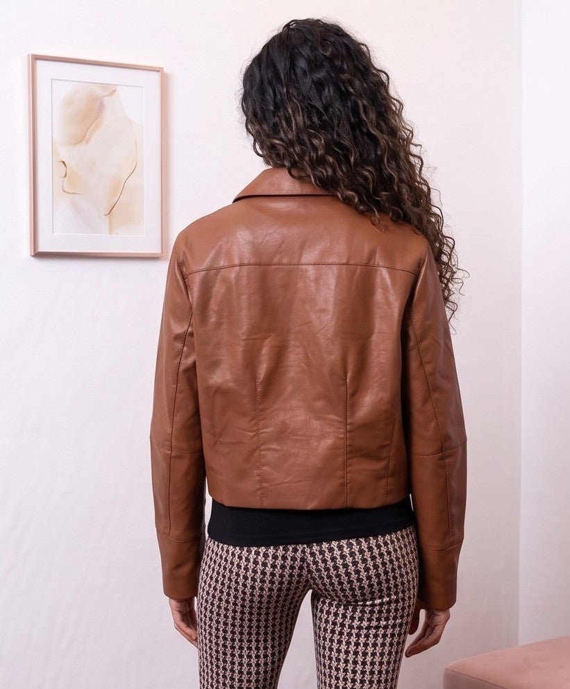 Chaqueta corta tipo cazadora para mujer en piel sintética efecto cuero con cuello camisero de solapa, cierre frontal abotonado, bolsillos diagonales ribeteados y corte recto relajado, disponible en color negro clásico y tono marrón caramelo teja sobre fondo de estudio elegante.