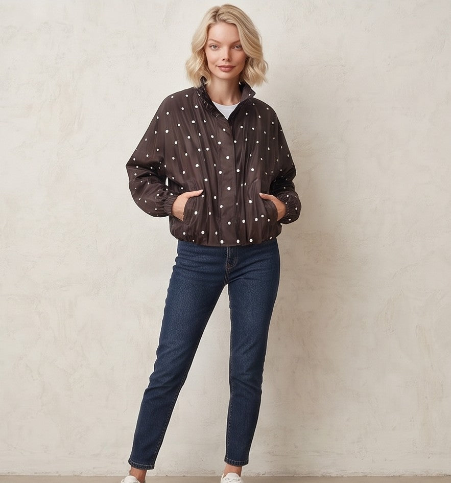 Chaqueta cortavientos de mujer con estampado de lunares, cuello alzado y cierre de cremallera, ideal para un look casual y urbano.