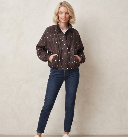 Chaqueta cortavientos de mujer con estampado de lunares, cuello alzado y cierre de cremallera, ideal para un look casual y urbano.