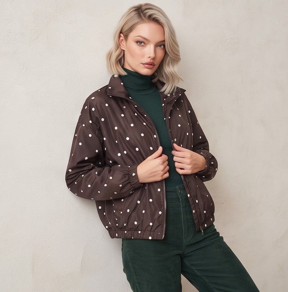 Chaqueta cortavientos de mujer con estampado de lunares, cuello alzado y cierre de cremallera, ideal para un look casual y urbano.