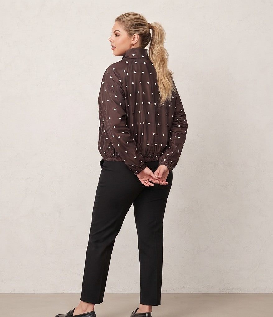 Chaqueta cortavientos de mujer con estampado de lunares, cuello alzado y cierre de cremallera, ideal para un look casual y urbano.