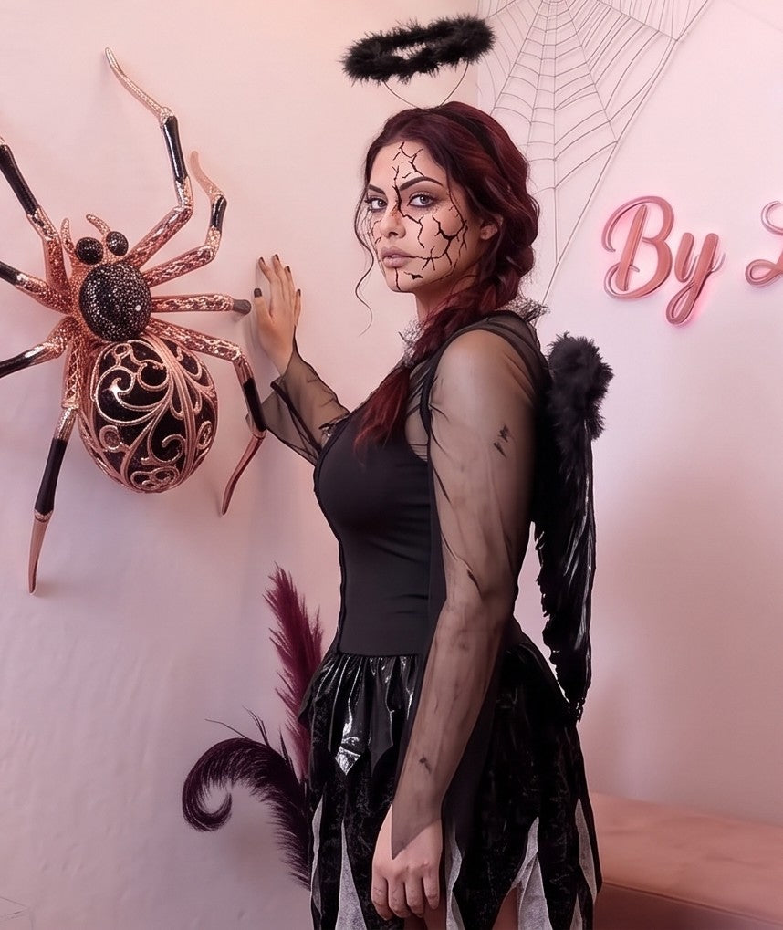 Disfraz femenino estilo fantasía de ángel caído y gótico compuesto por vestido corto con corsé de cordones entrelazados en el pecho, mangas acampanadas y falda asimétrica en picos confeccionada en terciopelo y malla de tul, acompañado de alas con plumas y diadema con aureola oscura.