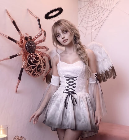 Disfraz femenino estilo fantasía de ángel caído y gótico compuesto por vestido corto con corsé de cordones entrelazados en el pecho, mangas acampanadas y falda asimétrica en picos confeccionada en terciopelo y malla de tul, acompañado de alas con plumas y diadema con aureola oscura.