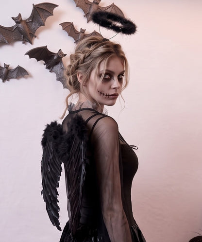Disfraz femenino estilo fantasía de ángel caído y gótico compuesto por vestido corto con corsé de cordones entrelazados en el pecho, mangas acampanadas y falda asimétrica en picos confeccionada en terciopelo y malla de tul, acompañado de alas con plumas y diadema con aureola oscura.