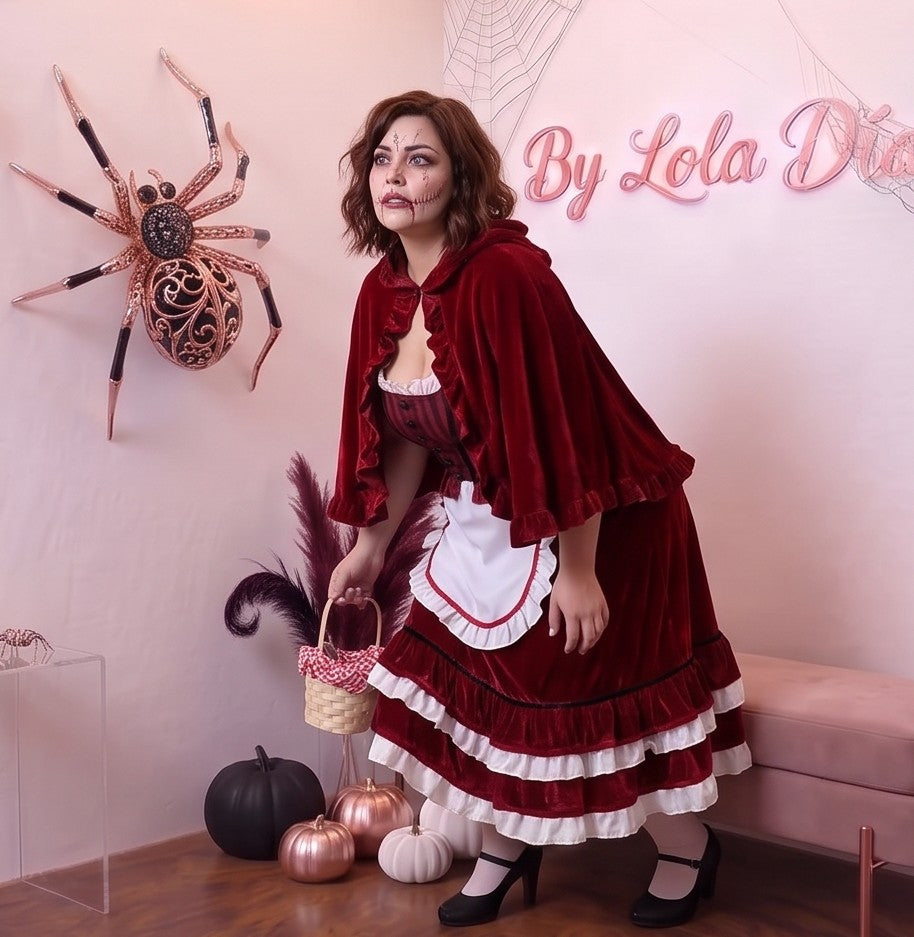 Disfraz de Caperucita Roja estilo gótico y fantasía para mujer, compuesto por vestido de terciopelo rojo vino con corpiño a rayas, delantal blanco con volantes, falda acampanada con ribete blanco y capa corta a juego con capucha amplia con fruncidos.