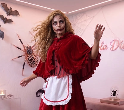 Disfraz de Caperucita Roja estilo gótico y fantasía para mujer, compuesto por vestido de terciopelo rojo vino con corpiño a rayas, delantal blanco con volantes, falda acampanada con ribete blanco y capa corta a juego con capucha amplia con fruncidos.