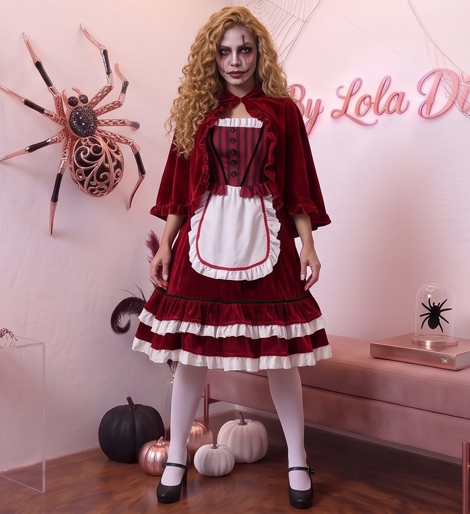 Disfraz de Caperucita Roja estilo gótico y fantasía para mujer, compuesto por vestido de terciopelo rojo vino con corpiño a rayas, delantal blanco con volantes, falda acampanada con ribete blanco y capa corta a juego con capucha amplia con fruncidos.