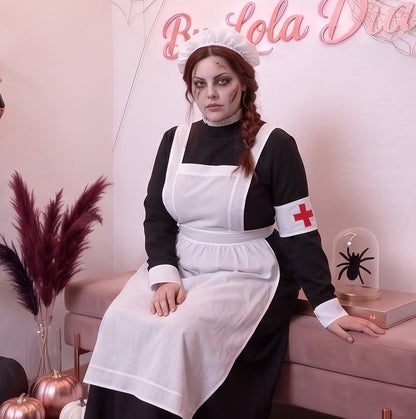Disfraz vintage de enfermera de época victoriana o monja médica para mujer, compuesto por vestido largo negro de cuello alto y manga larga con puños blancos, delantal blanco con tirantes cruzados a la espalda, brazalete blanco con cruz roja y cofia blanca fruncida a juego