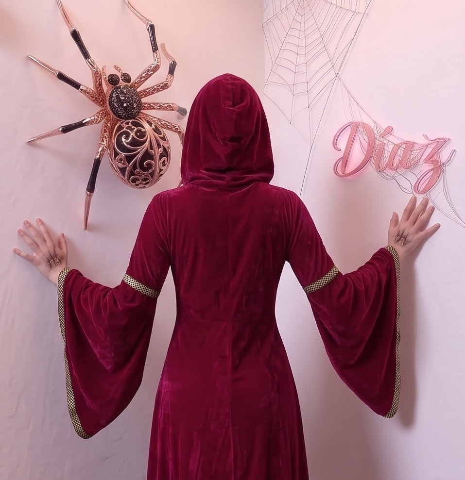 Disfraz medieval y gótico de mujer con vestido largo hasta los pies en tejido de terciopelo rojo burdeos, detalle frontal drapeado en tono crema y corsé con lazos dorados cruzados, mangas largas acampanadas acampanadas con ribetes dorados y capucha holgada integrada, ideal para caracterización teatral, temática de época y Halloween.