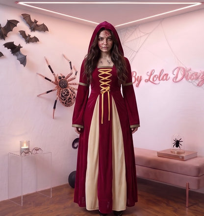 Disfraz medieval y gótico de mujer con vestido largo hasta los pies en tejido de terciopelo rojo burdeos, detalle frontal drapeado en tono crema y corsé con lazos dorados cruzados, mangas largas acampanadas acampanadas con ribetes dorados y capucha holgada integrada, ideal para caracterización teatral, temática de época y Halloween.