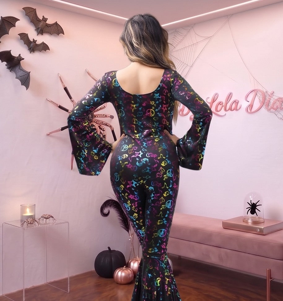 Mono ajustado de estilo disco años 70 de poliéster elástico, con cuello amplio en pico, mangas acampanadas y perneras de pata de elefante, decorado con un estampado retro de notas musicales, estrellas y símbolos de la paz en tonos multicolor vibrantes sobre base lisa.