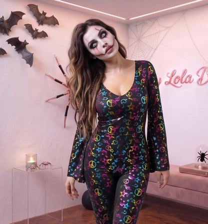 Mono ajustado de estilo disco años 70 de poliéster elástico, con cuello amplio en pico, mangas acampanadas y perneras de pata de elefante, decorado con un estampado retro de notas musicales, estrellas y símbolos de la paz en tonos multicolor vibrantes sobre base lisa.