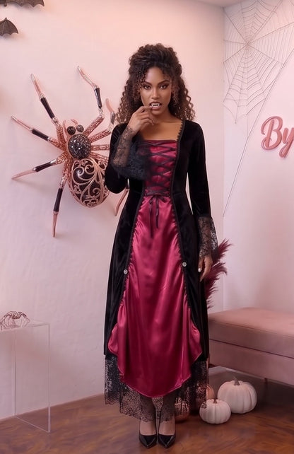 disfraz de vampiresa gótica compuesto por un vestido de terciopelo negro y satén rojo. El vestido presenta un corpiño con cordones frontales en el escote, mangas de encaje negro acampanadas y una falda larga de encaje con vuelo.