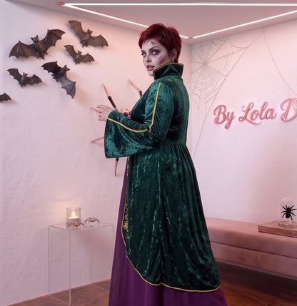Disfraz de bruja medieval inspirado en Winifred Sanderson con vestido largo en dos piezas simuladas: túnica exterior de terciopelo verde esmeralda con cuello alzado, mangas acampanadas con ribetes dorados y bordados rúnicos en el pecho, sobre falda interior fluida en tono morado púrpura con corsé ajustable de cordones amarillos. Tallas Grandes, Curvy, XXXL.