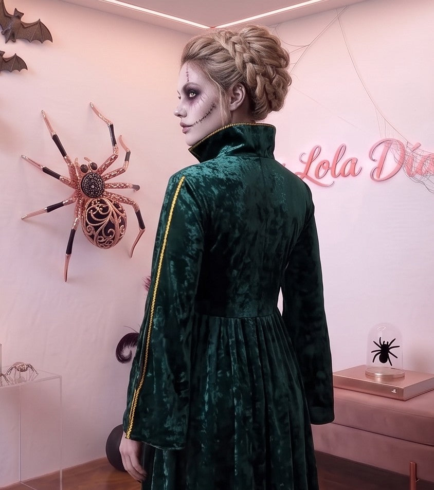 Disfraz de bruja medieval inspirado en Winifred Sanderson con vestido largo en dos piezas simuladas: túnica exterior de terciopelo verde esmeralda con cuello alzado, mangas acampanadas con ribetes dorados y bordados rúnicos en el pecho, sobre falda interior fluida en tono morado púrpura con corsé ajustable de cordones amarillos.