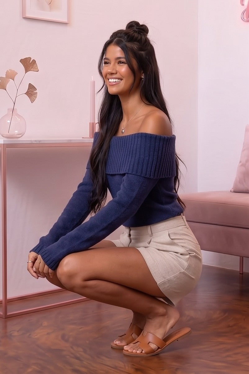 Jersey corto de punto fino acanalado para mujer con escote barco de hombros caídos y manga larga, disponible en azul marino, blanco roto y negro clásico sobre fondo de boutique.