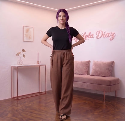 Pantalón ancho para mujer en mezcla de algodón y lino, diseño recto y fluido de tiro alto con cintura elástica fruncida, bolsillos funcionales y detalle de cordón ajustable anudado en el lateral de la cintura, disponible en una variedad de colores lisos.