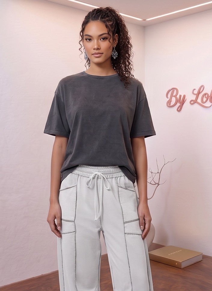 Pantalón fluido estilo bombacho wide leg para mujer con cintura elástica de cordón ajustable, costuras vistas en contraste y bolsillos cargo laterales geométricos, disponible en 8 colores: amarillo pastel, azul celeste, verde esmeralda, blanco tiza, beige arena, marrón chocolate, azul marino y negro con pespuntes dorados