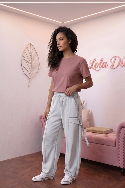 Pantalón fluido estilo bombacho wide leg para mujer con cintura elástica de cordón ajustable, costuras vistas en contraste y bolsillos cargo laterales geométricos, disponible en 8 colores: amarillo pastel, azul celeste, verde esmeralda, blanco tiza, beige arena, marrón chocolate, azul marino y negro con pespuntes dorados