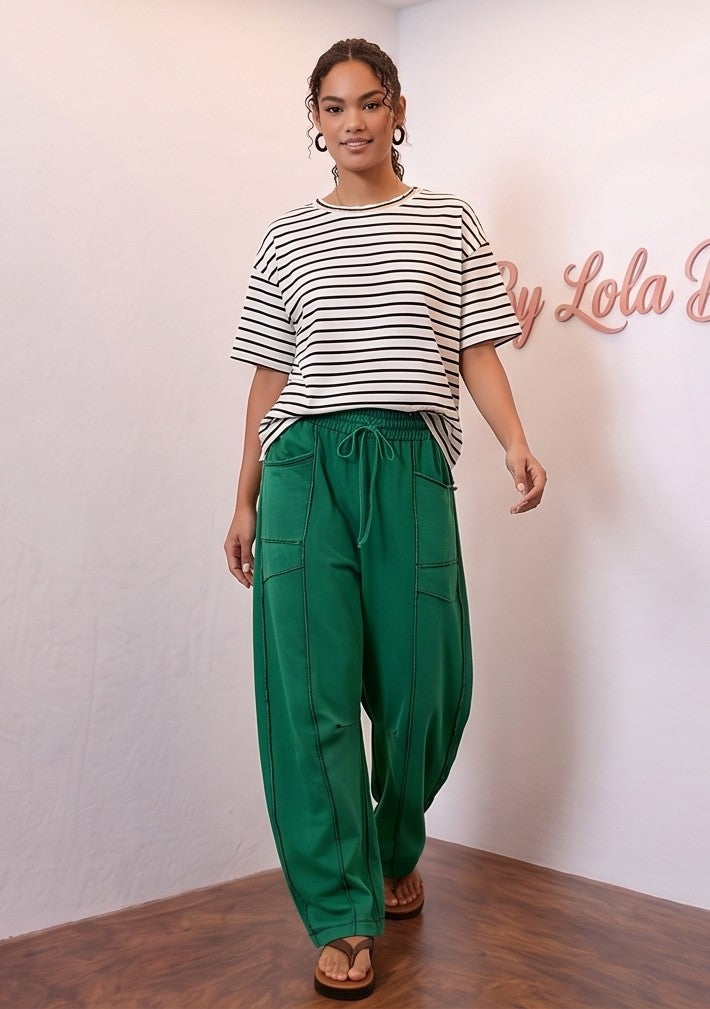 Pantalón fluido estilo bombacho wide leg para mujer con cintura elástica de cordón ajustable, costuras vistas en contraste y bolsillos cargo laterales geométricos, disponible en 8 colores: amarillo pastel, azul celeste, verde esmeralda, blanco tiza, beige arena, marrón chocolate, azul marino y negro con pespuntes dorados