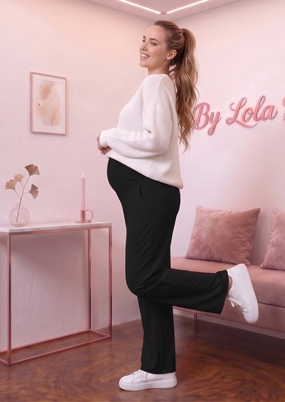 Detalle del dobladillo, costuras y acabado de Pantalón premamá de corte recto y pierna ancha para embarazo y posparto, disponible en color negro, gris claro vigoré y gris marengo oscuro. Confeccionado en tejido elástico extrasuave efecto seda, con banda sobre la barriga con elástico y botón regulable interior, bolsillos laterales y caída holgada.