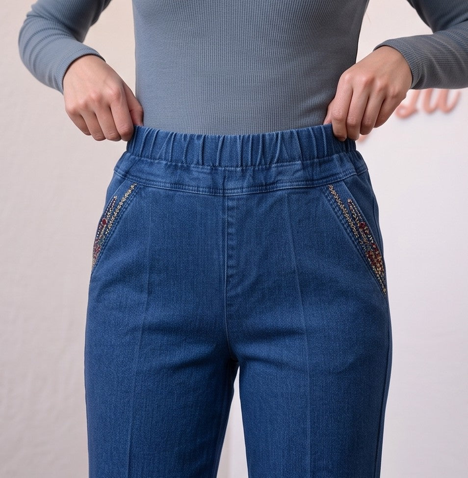 Pantalón vaquero de mujer de tiro alto, elástico, con detalle de cremallera decorativa lateral y diseño clásico de cinco bolsillos, disponible en tres colores vibrantes: azul denim oscuro, azul denim medio y negro.