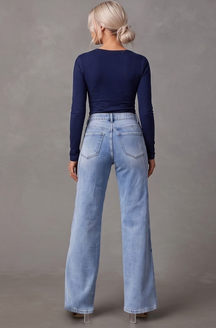 Pantalón vaquero de mujer wide leg de tiro alto en tono azul claro desgastado, con detalle de costuras verticales diagonales al frente y bolsillos traseros estructurados
