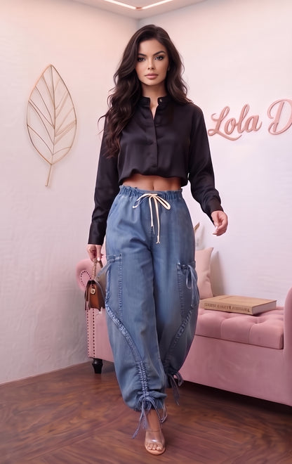 Pantalón largo estilo trendy de mezclilla azul para mujer, corte holgado (loose fit), talle de cintura media con cordones de ajuste y lazada en la cintura, bolsillos laterales estilo cargo con detalles fruncidos y cordones regulables en los tobillos.