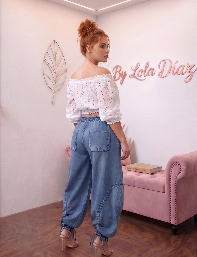Pantalón largo estilo trendy de mezclilla azul para mujer, corte holgado (loose fit), talle de cintura media con cordones de ajuste y lazada en la cintura, bolsillos laterales estilo cargo con detalles fruncidos y cordones regulables en los tobillos.