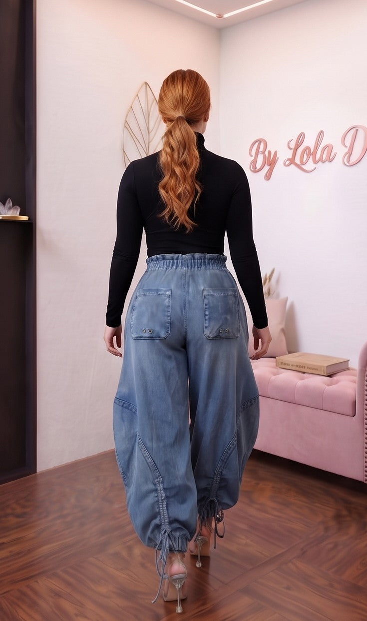 Pantalón largo estilo trendy de mezclilla azul para mujer, corte holgado (loose fit), talle de cintura media con cordones de ajuste y lazada en la cintura, bolsillos laterales estilo cargo con detalles fruncidos y cordones regulables en los tobillos.