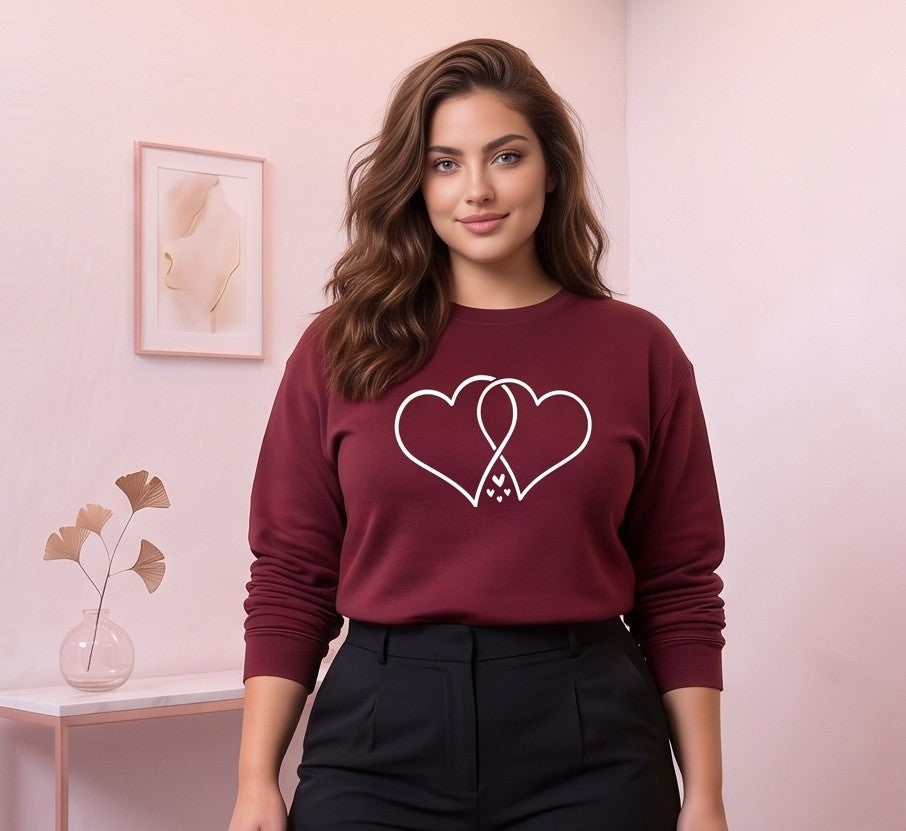 Sudadera de algodón para mujer con corte holgado y cuello redondo, manga larga con puños elásticos y estampado gráfico de dos corazones entrelazados en el pecho, disponible en siete colores: blanco, negro, gris, rosa, amarillo, verde y vino tinto