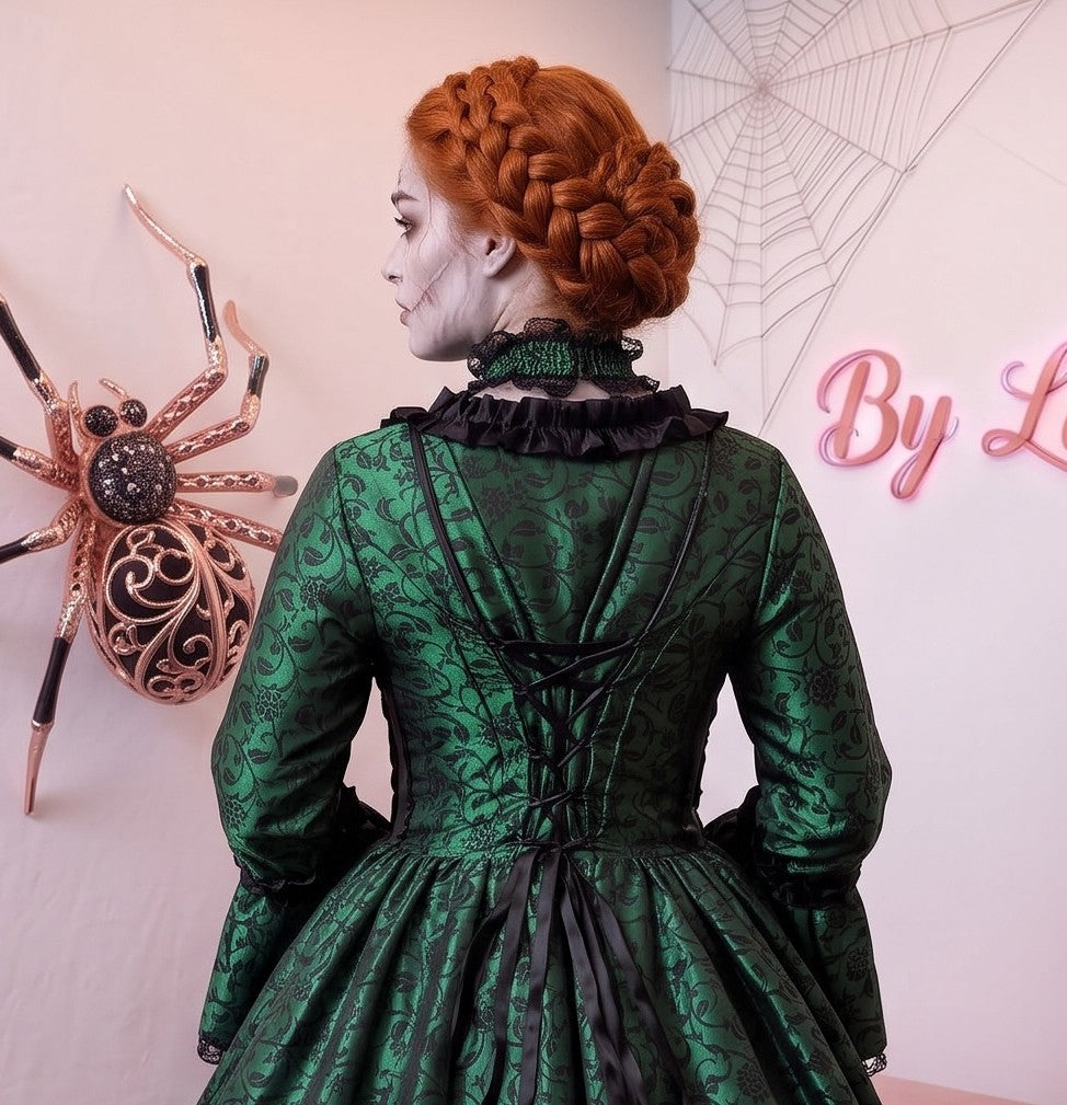 Vestido de época victoriana y corte medieval para mujer en tejido de damasco satinado con estampado floral barroco y panel frontal liso en contraste; presenta escote cuadrado ribeteado con encaje fruncido, mangas largas acampanadas estilo campana, corpiño ajustable tipo corsé en la espalda con lazada y gargantilla a juego. Disponible en cinco variantes de color combinadas con negro: verde esmeralda, morado berenjena, rojo granate, azul petróleo y blanco plateado.Vestido de época victoriana y corte medieval 